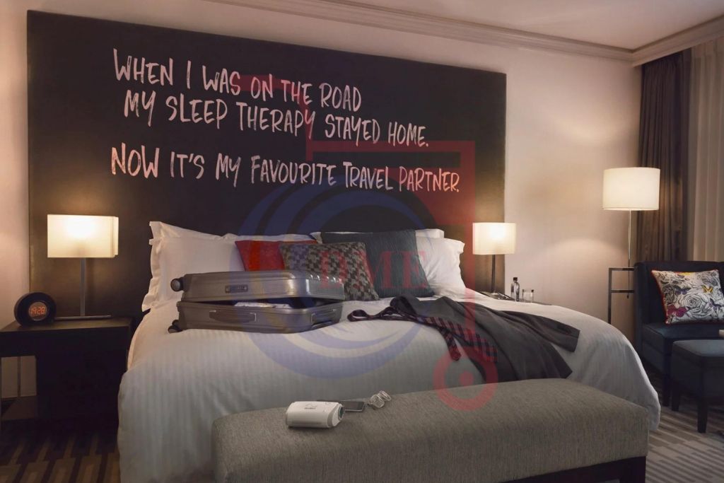 Resmed AirMini AutoSet Portable CPAP device placed on a bed in a modern hotel room