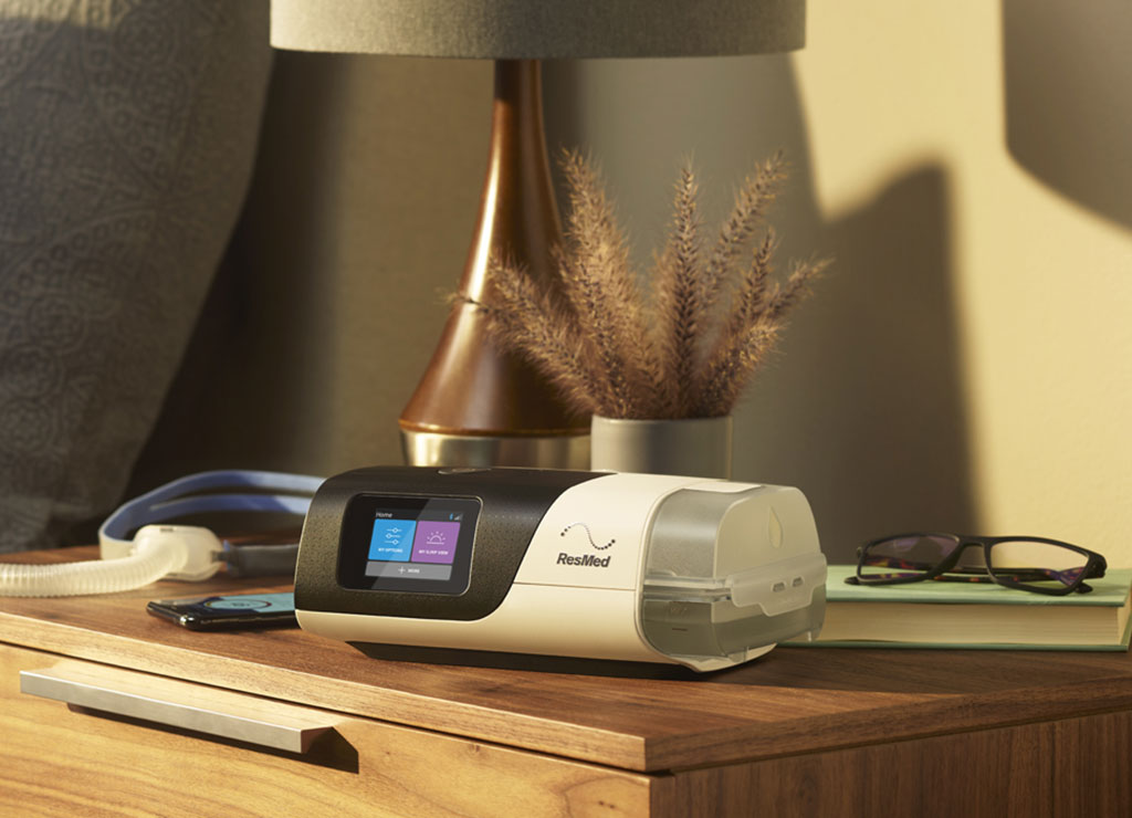 Resmed AirSense 11 CPAP machine on wooden nightstand with lamp and eyeglasses nearby